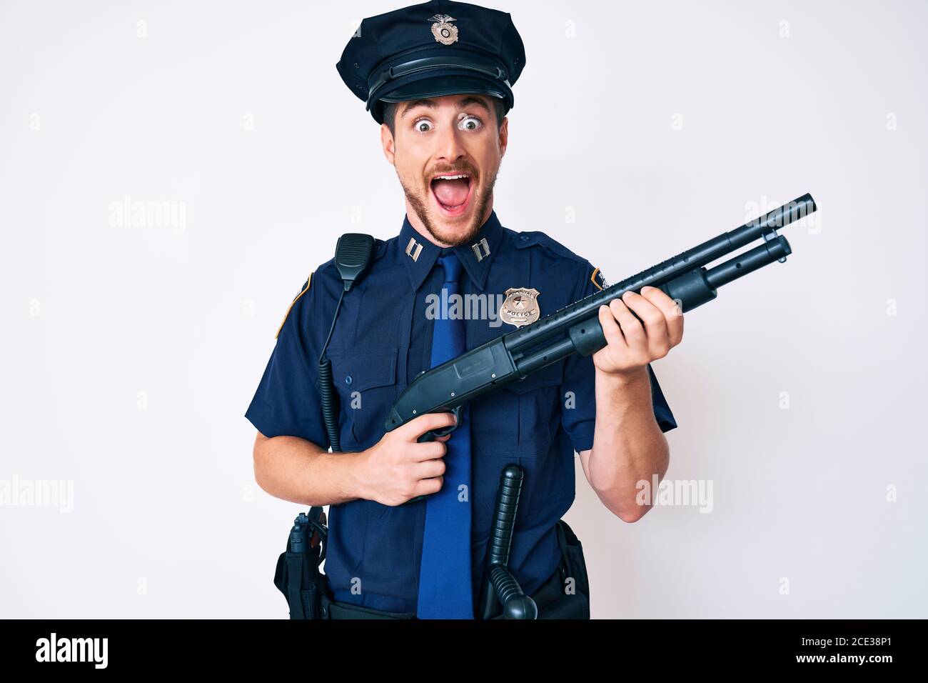 Young caucasian man wearing police uniform holding shotgun celebrating ...