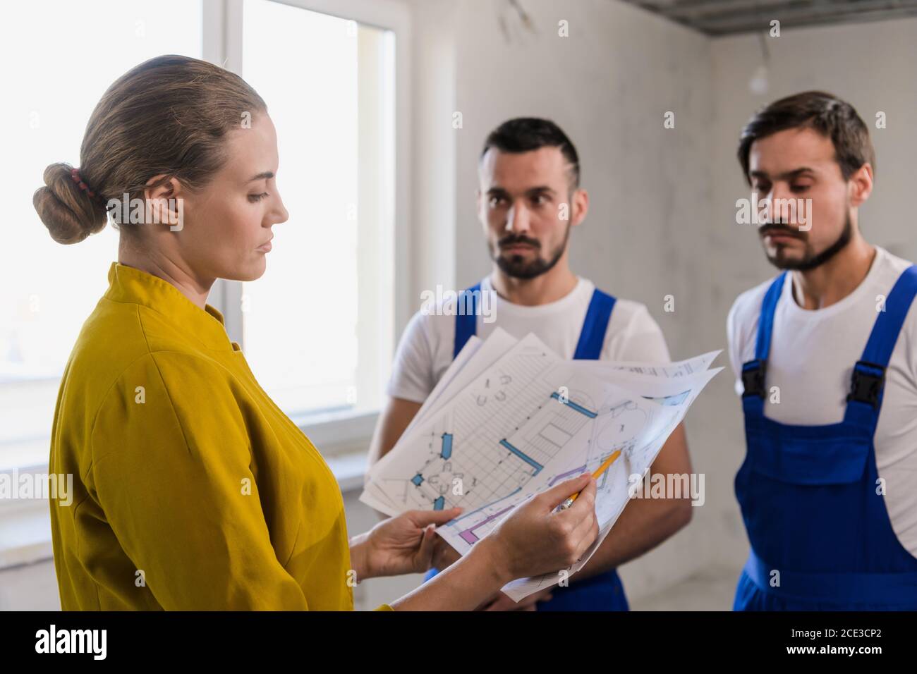 A forewoman talking with the male builders and considers the scheme of the house Stock Photo