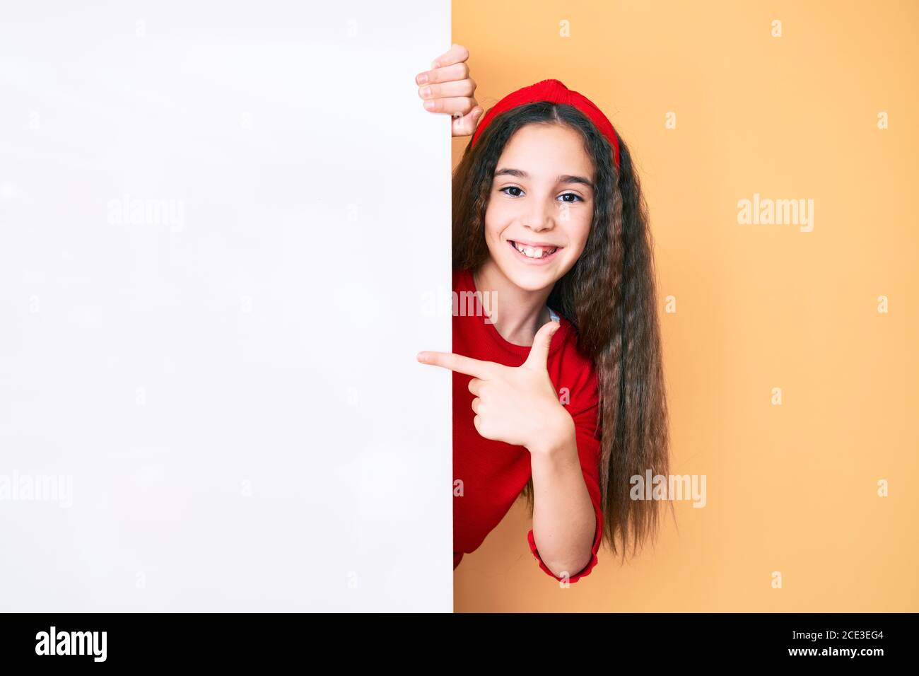 Cute hispanic child girl holding blank empty banner smiling happy ...