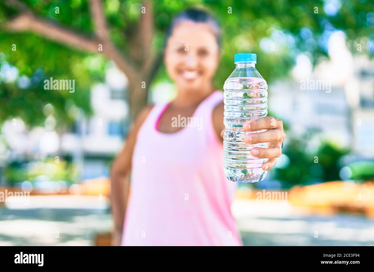 Middle age sportswoman smiling happy holding bottle of water at the ...