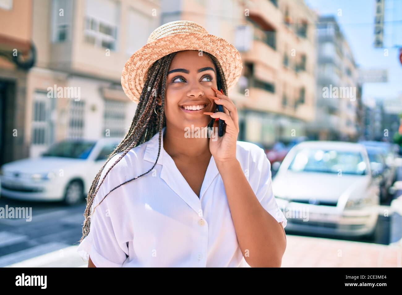 Young african american woman with braids smiling happy spaking on the phone outdoors on a sunny day of summer Stock Photo