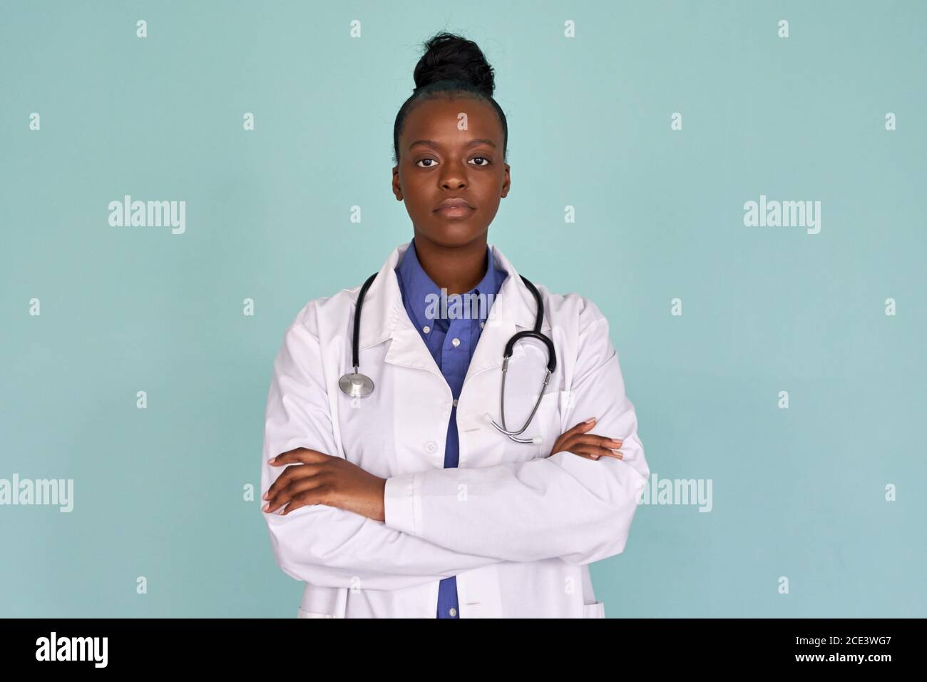 Confident african female doctor looking at camera on mint background, portrait. Stock Photo