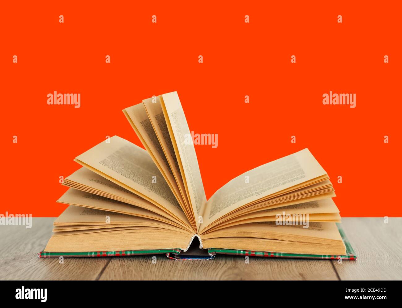 Open book textbook in colorful cover on a orange red background. Back to school distance home education.Quarantine concept of stay home Stock Photo