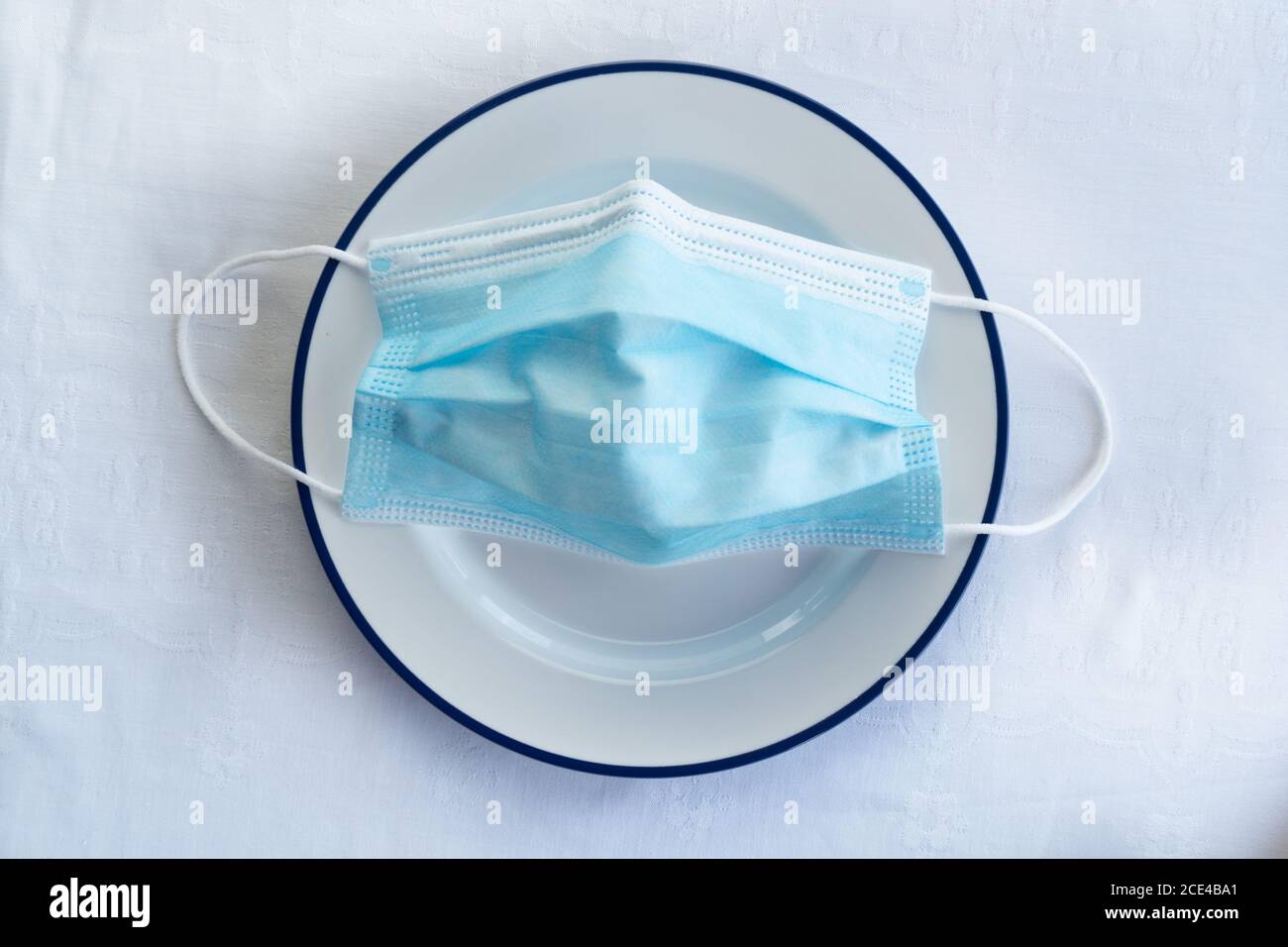 blue protection face mask for corona virus or covid 19 health prevention on white  food dish in restaurant Stock Photo