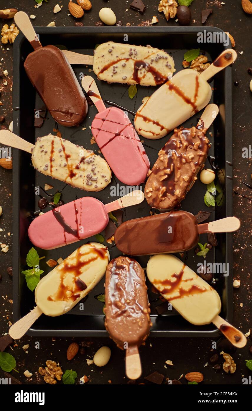 Assortment of various popsicle ice cream, white and dark chocolate, with almonds, rusty background Stock Photo