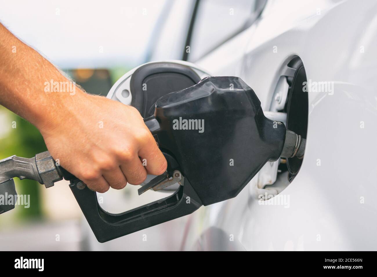 Car pumping gas at gas pump. Closeup of man pumping gasoline fuel in