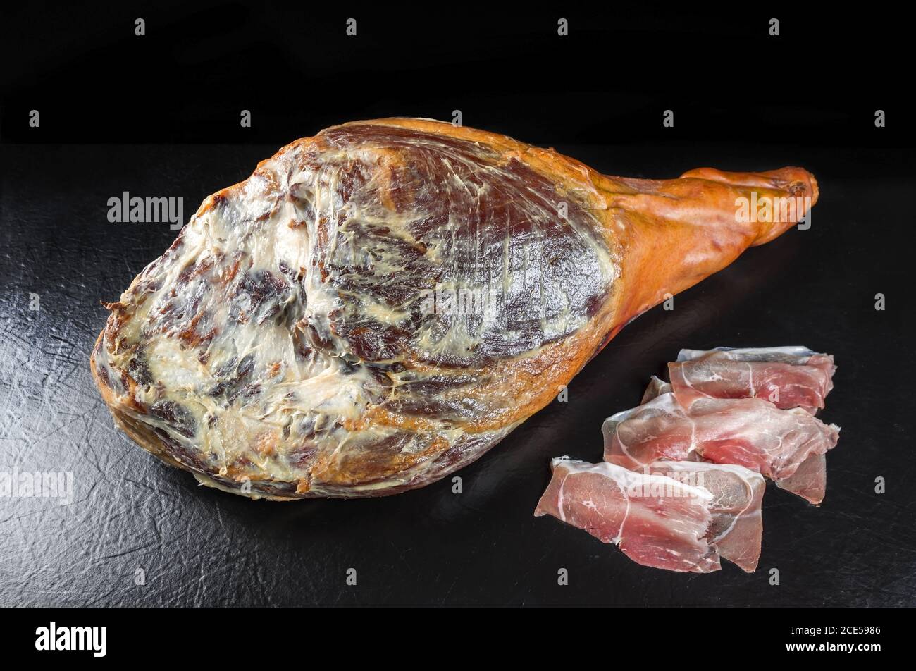 Traditional Spanish jamon Iberico dry aged haunch of a duroc pork as  closeup offered on black background Stock Photo - Alamy