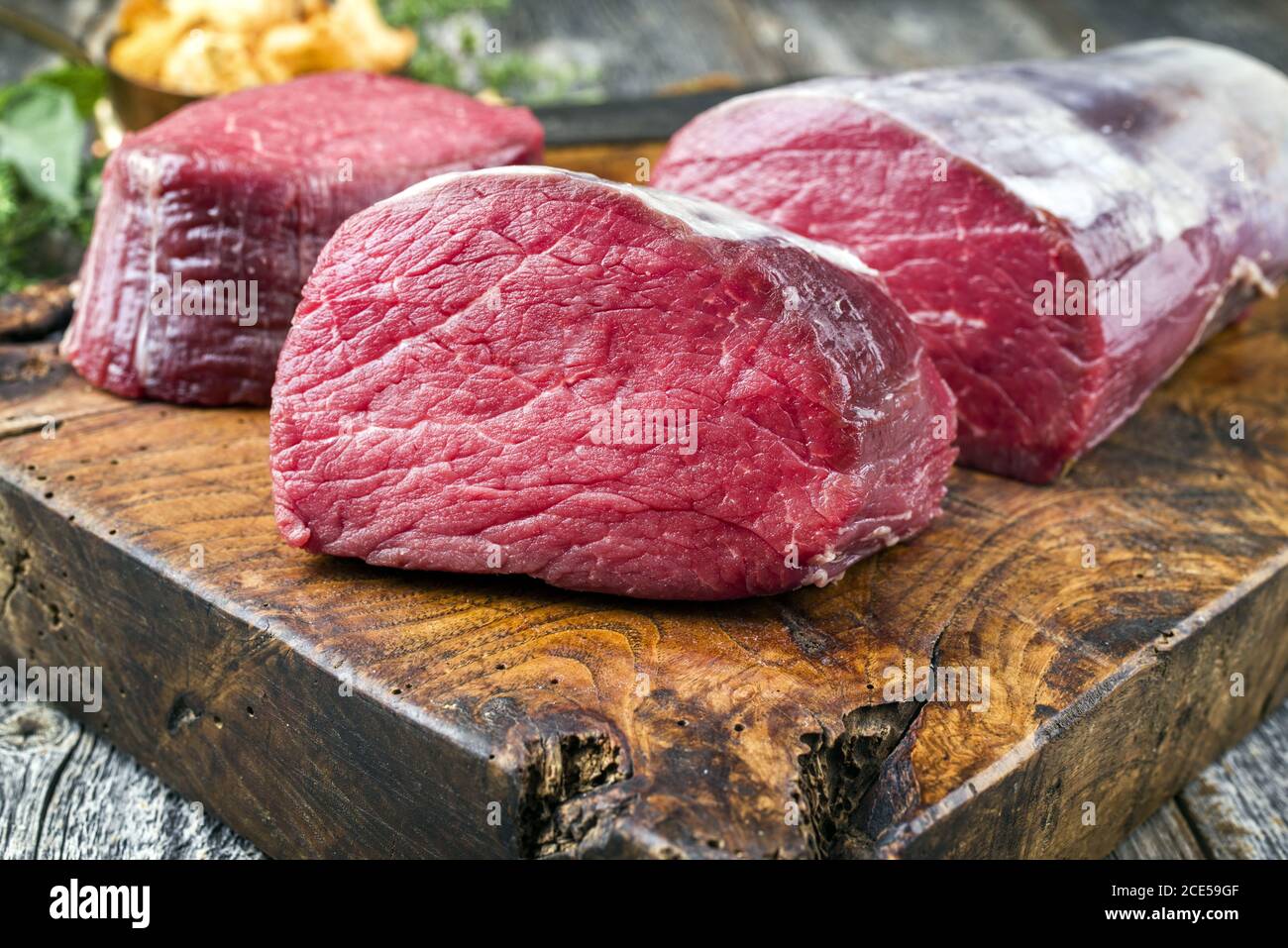 Dry aged beef fillet steak natural as closeup with chanterelles on a wooden cutting board Stock Photo