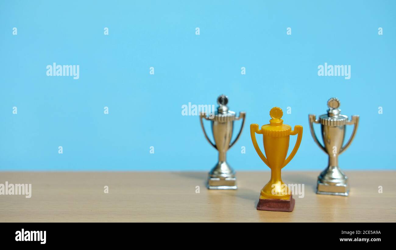 Golden trophy with two silver trophy at back above wooden table Stock Photo