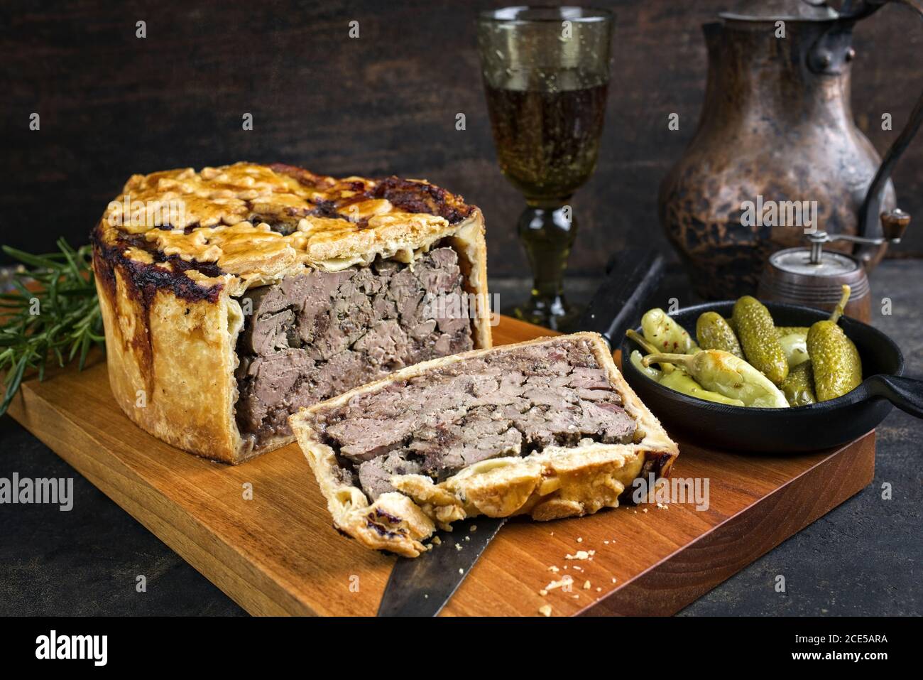 Traditional French Pate en croute with goose liver as closeup with gherkin and pepperoni on a