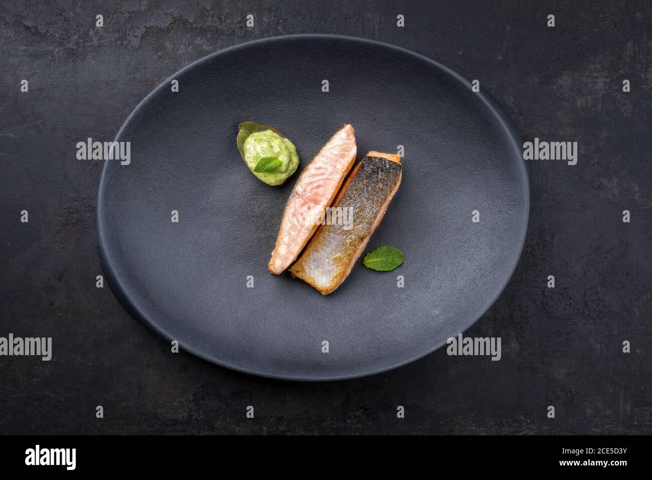 Minimalistic design salmon fish filet glazed with avocado and wasabi creme in artichoke leaf as top view on a modern design cast Stock Photo