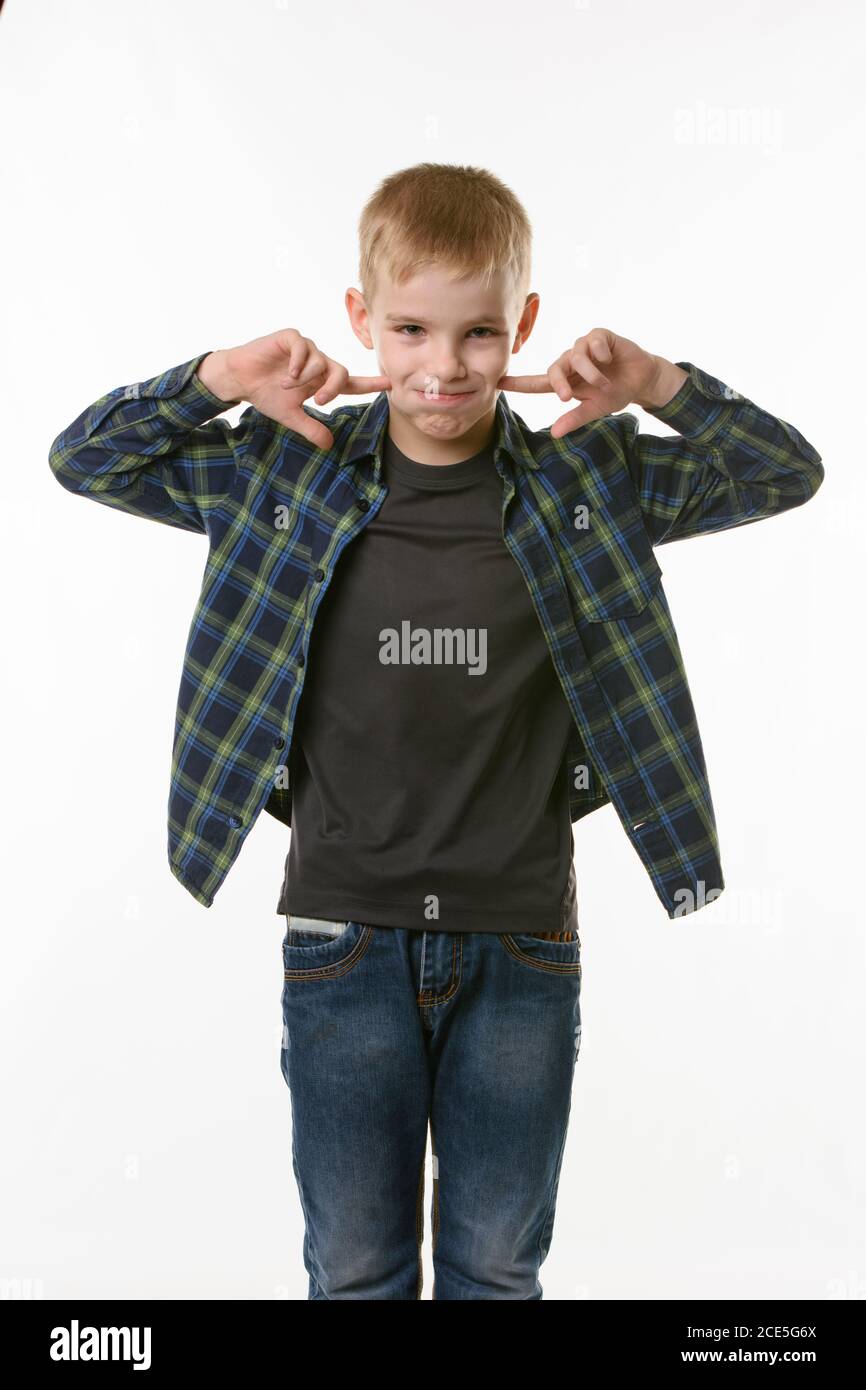 boy on a white background in a plaid shirt blows his cheeks with his fingers Stock Photo