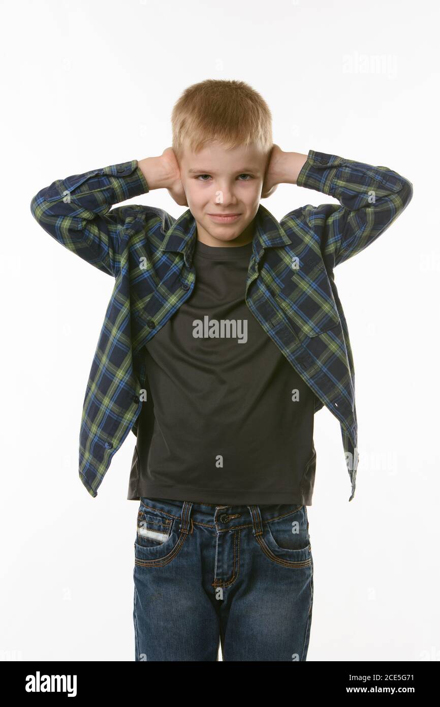 Boy covers his ears with his hands on a white background in everyday clothes Stock Photo