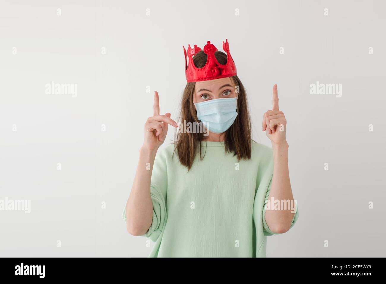 Woman in mask and crown pointing up Stock Photo
