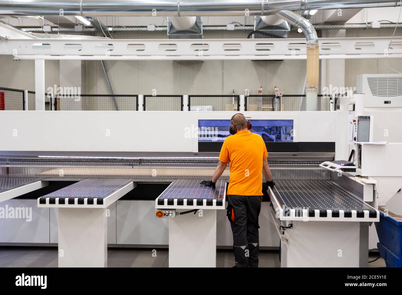 A worker works on woodworking machine in a factory. Wood and wood-based ...