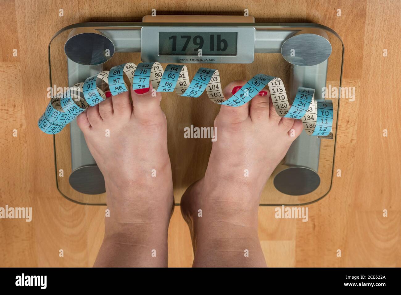https://c8.alamy.com/comp/2CE622A/a-woman-stands-with-two-feet-on-a-scale-overweight-concept-2CE622A.jpg