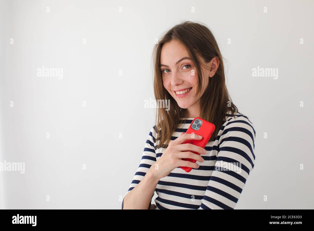 Smiling woman surfing smartphone at home Stock Photo