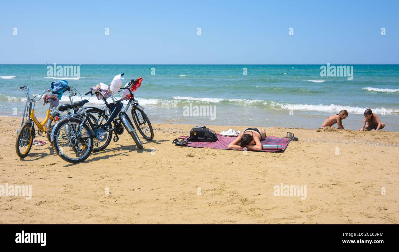 On the sandy seashore, a family arriving on bicycles rests Stock Photo