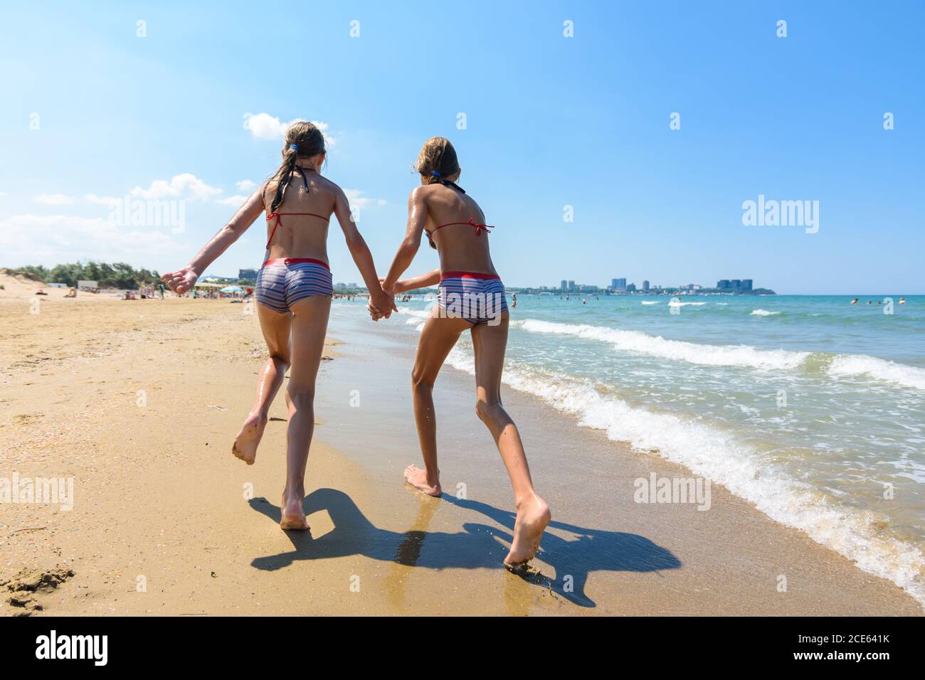 Two girls run along the a beach Stock Photo