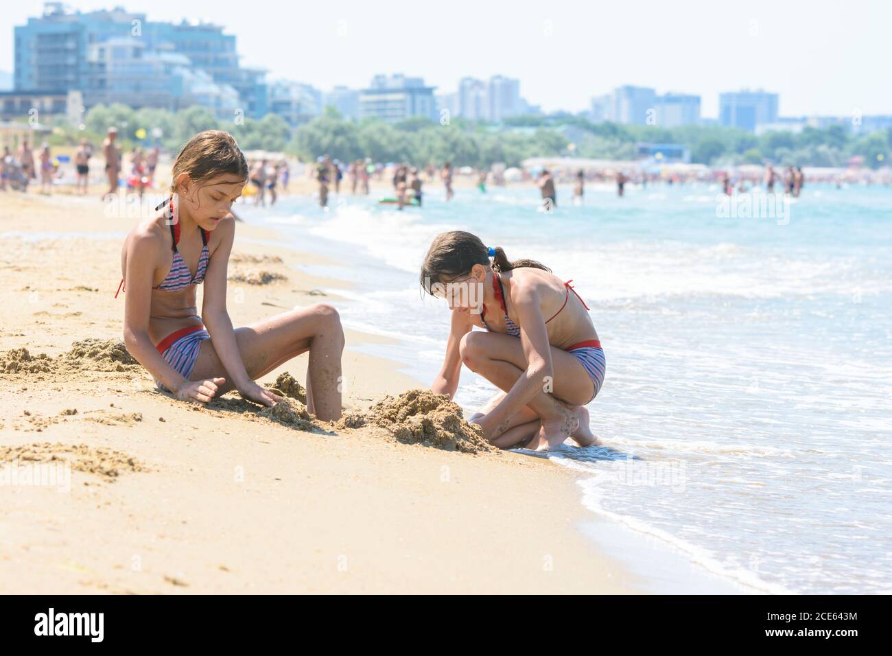 Girls on the seashore make sand castles Stock Photo