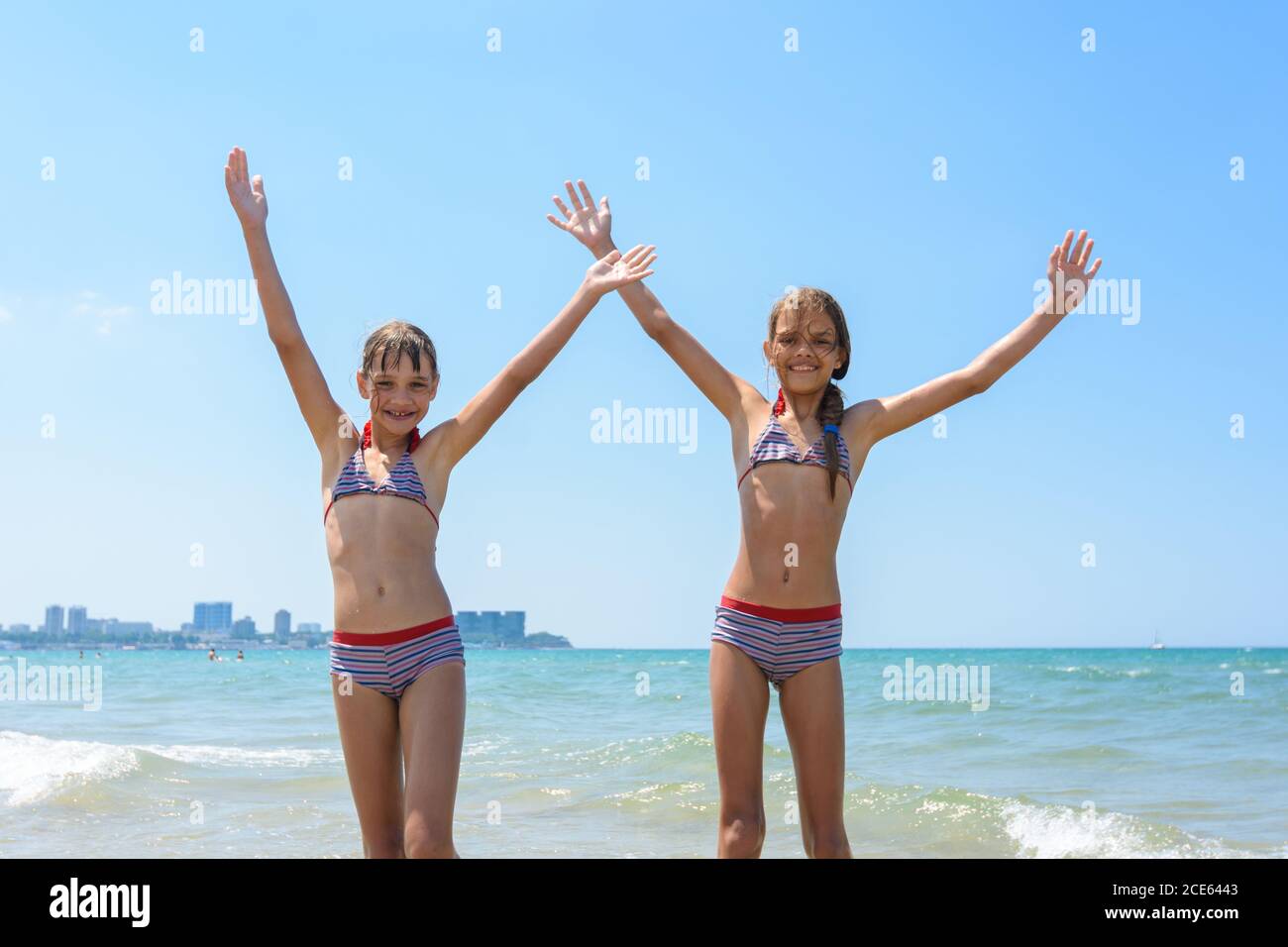 Two girls joyfully raised their hands up on the seashore Stock Photo