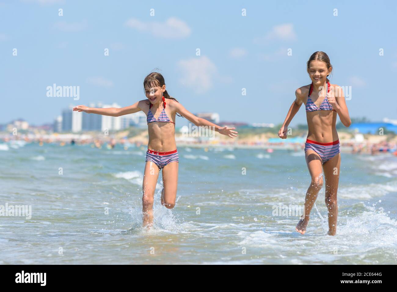 Two girls joyfully run along the seashore on a warm summer day Stock Photo