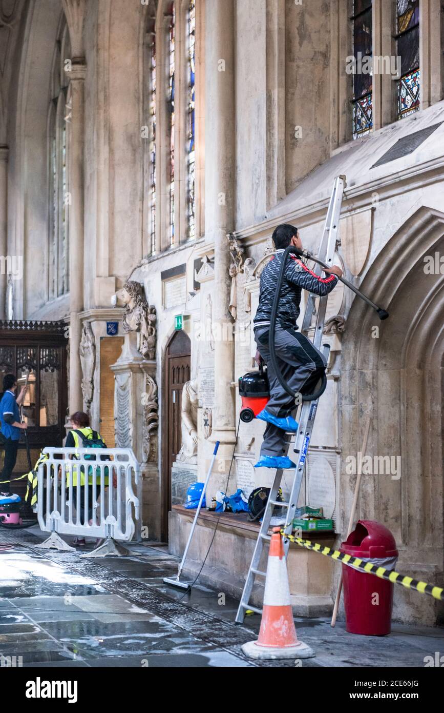 Cleaning of the interior stone work, Bath Abbey, England. working man on on ladder. Wet soapy stone floor being cleaned. Red and orange cone in use. Stock Photo