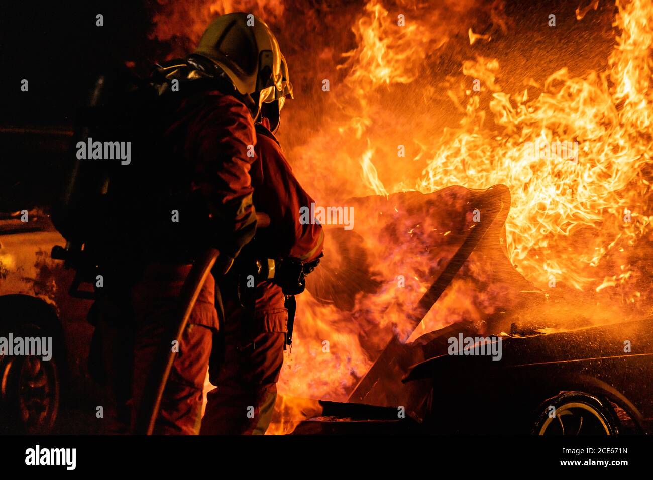 Firefighters spraying down fire flame from car accident Stock Photo