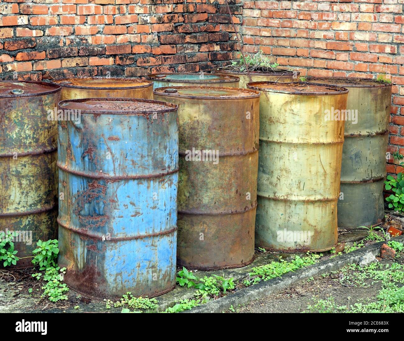 Corroding oil drums in a deserted building pollute the ground Stock Photo