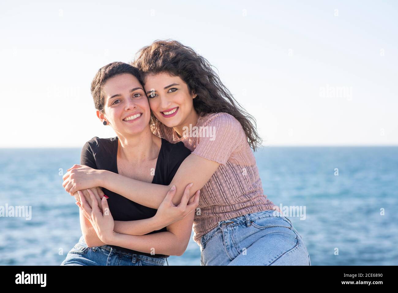 Two female friends hugging by the beach Stock Photo