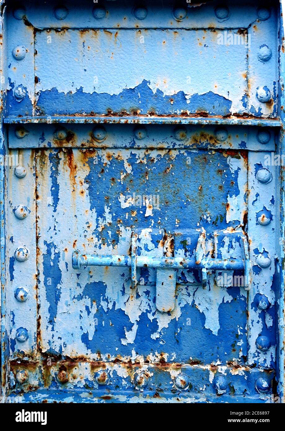 A heavy duty iron door with a bolt and old paint peeling off Stock Photo Alamy