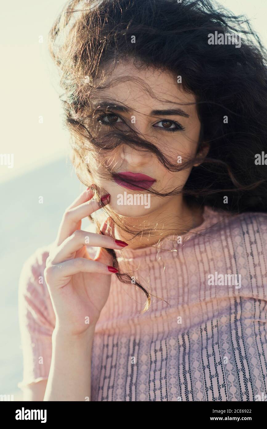 Beautiful young woman hand touching face looking at camera Stock Photo ...