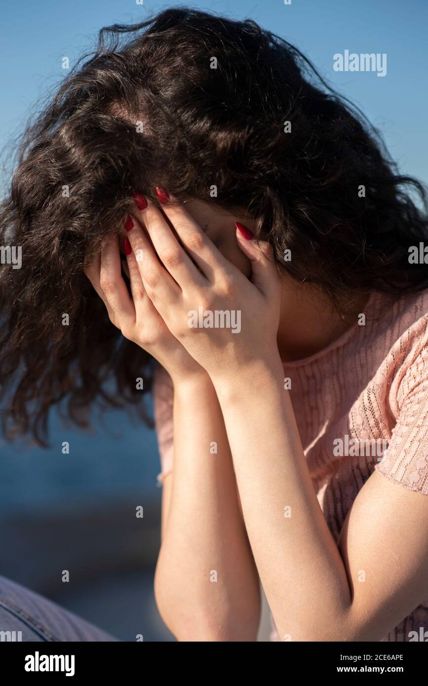 Stressed woman head in hands crying by the sea Stock Photo
