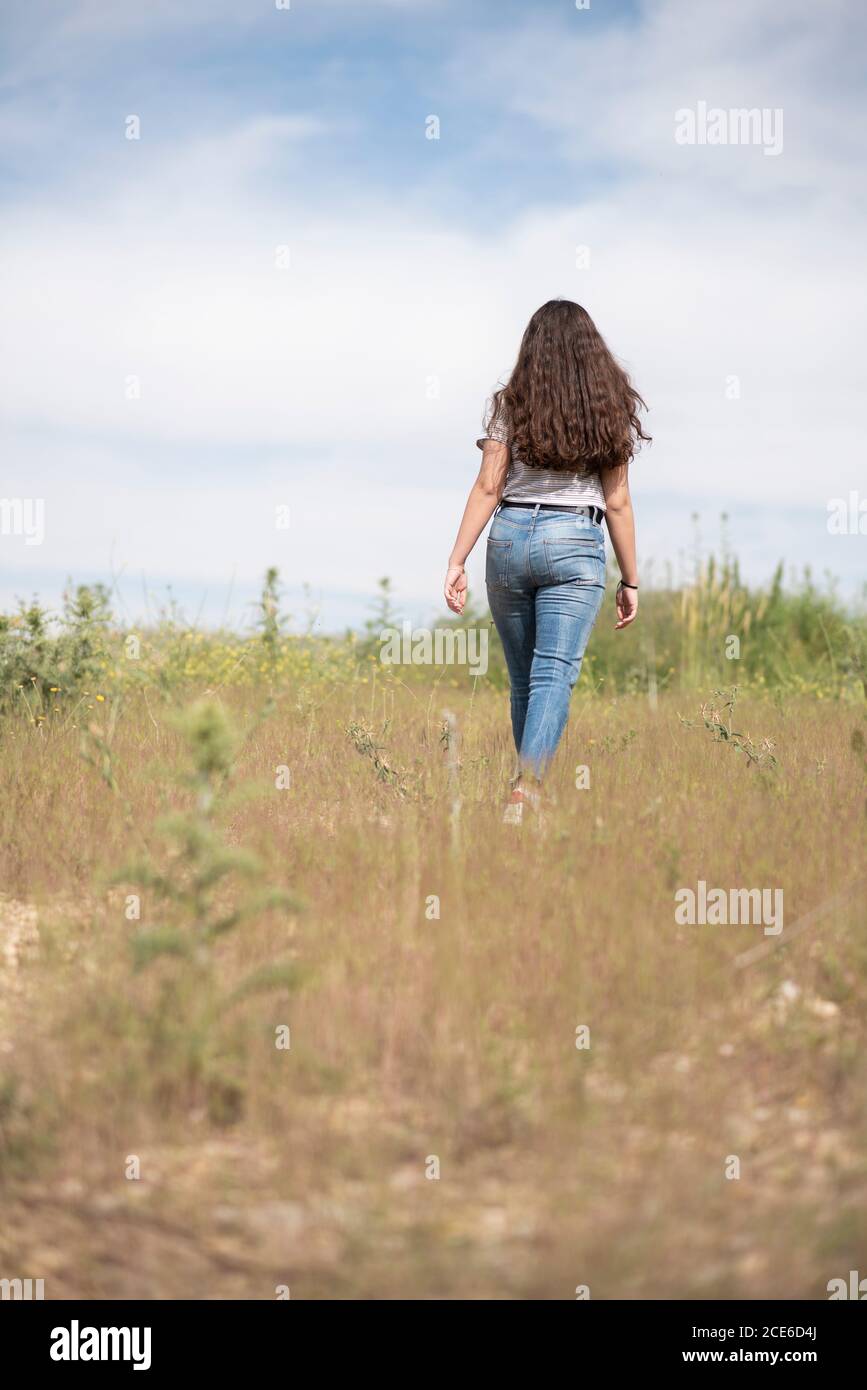 Rear view of teenage girl walking in field Stock Photo