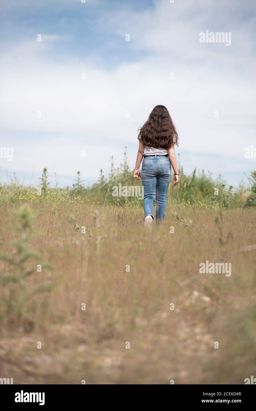 Rear view of teenage girl walking in field Stock Photo - Alamy