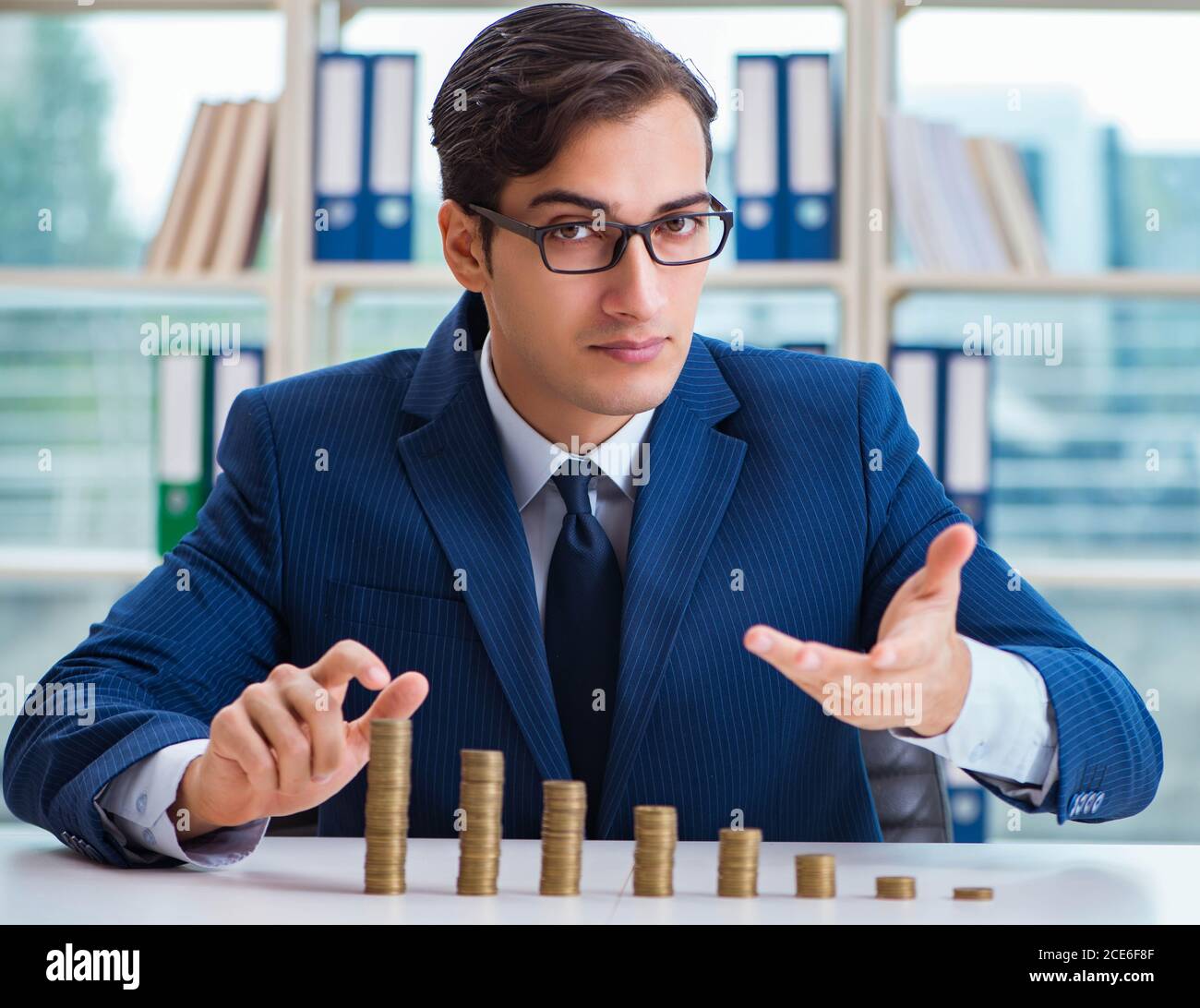 The businessman with stacks of coins in the office Stock Photo - Alamy