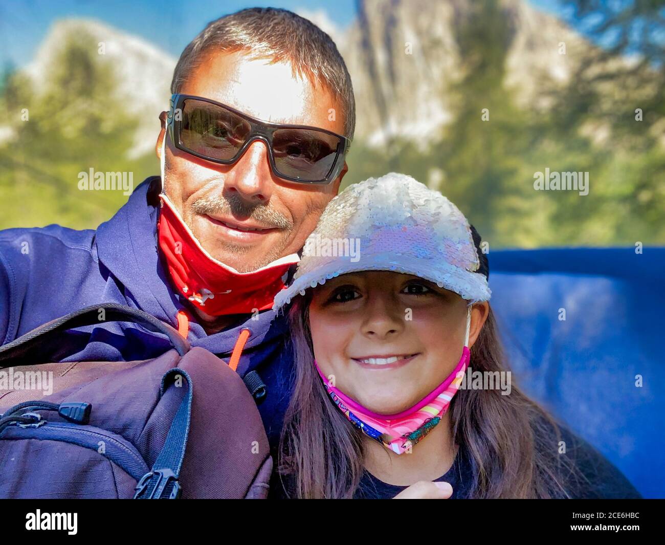 Man with his daughter happy during a mountain excursion, wearing masks Stock Photo
