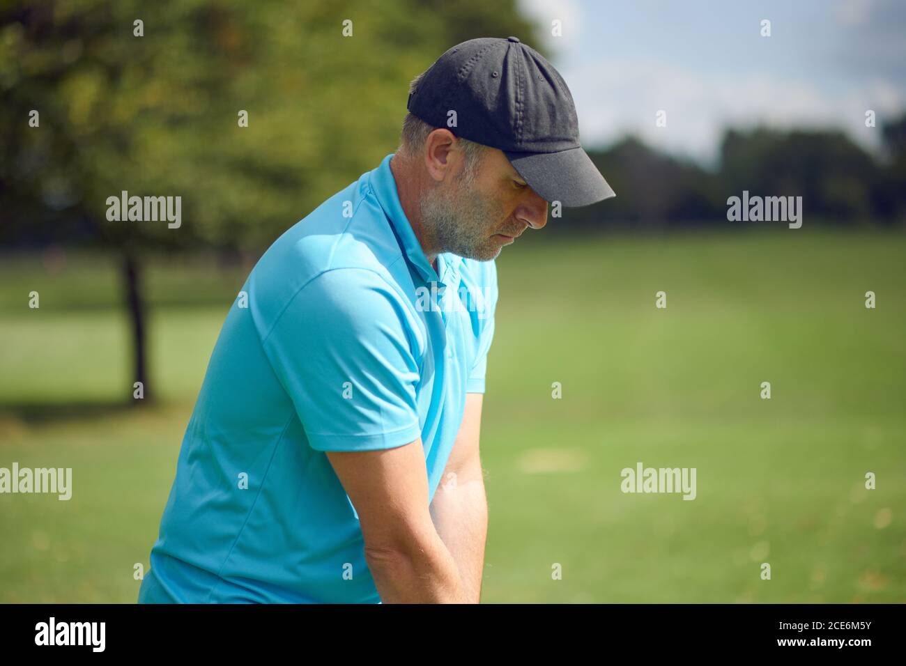 Male golfer swinging at the ball with an iron club as he takes his shot on a golf course in a closeup upper body view in a healthy active lifestyle co Stock Photo