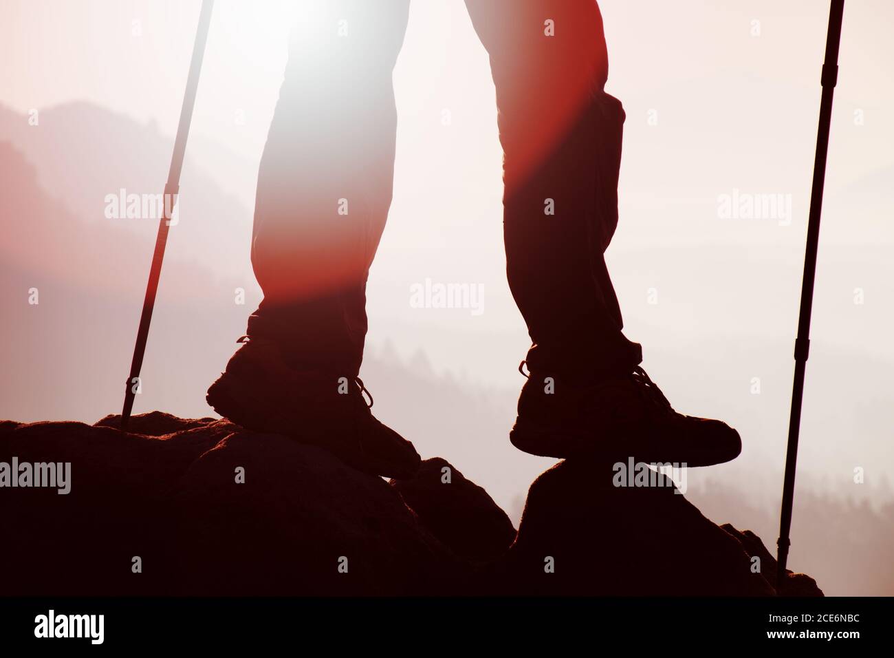 Man hiker legs in boots and poles stand on mountain Stock Photo
