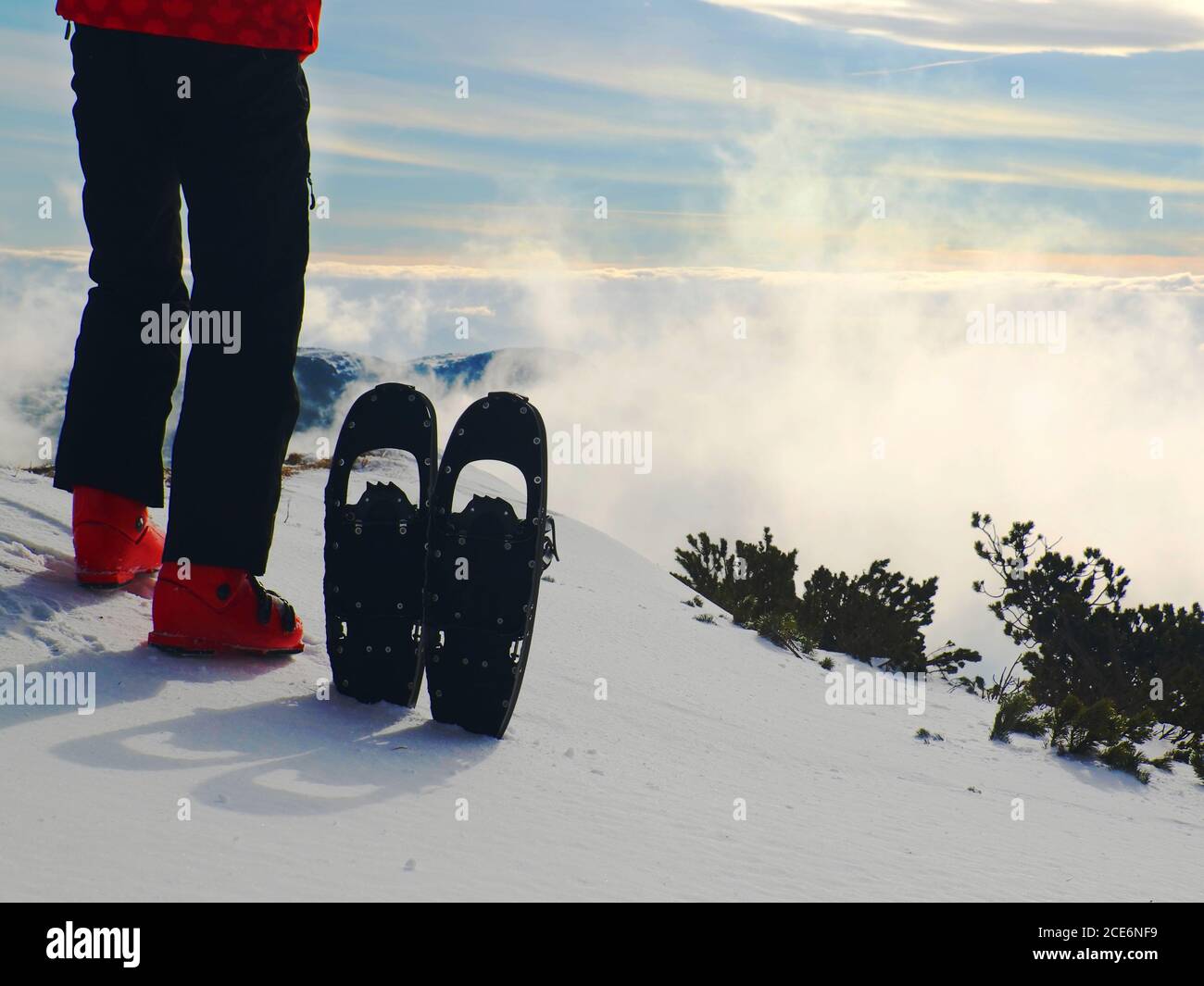 Skier in red winter jacket with  fun snowshoes stay in snow in mountains. Stock Photo