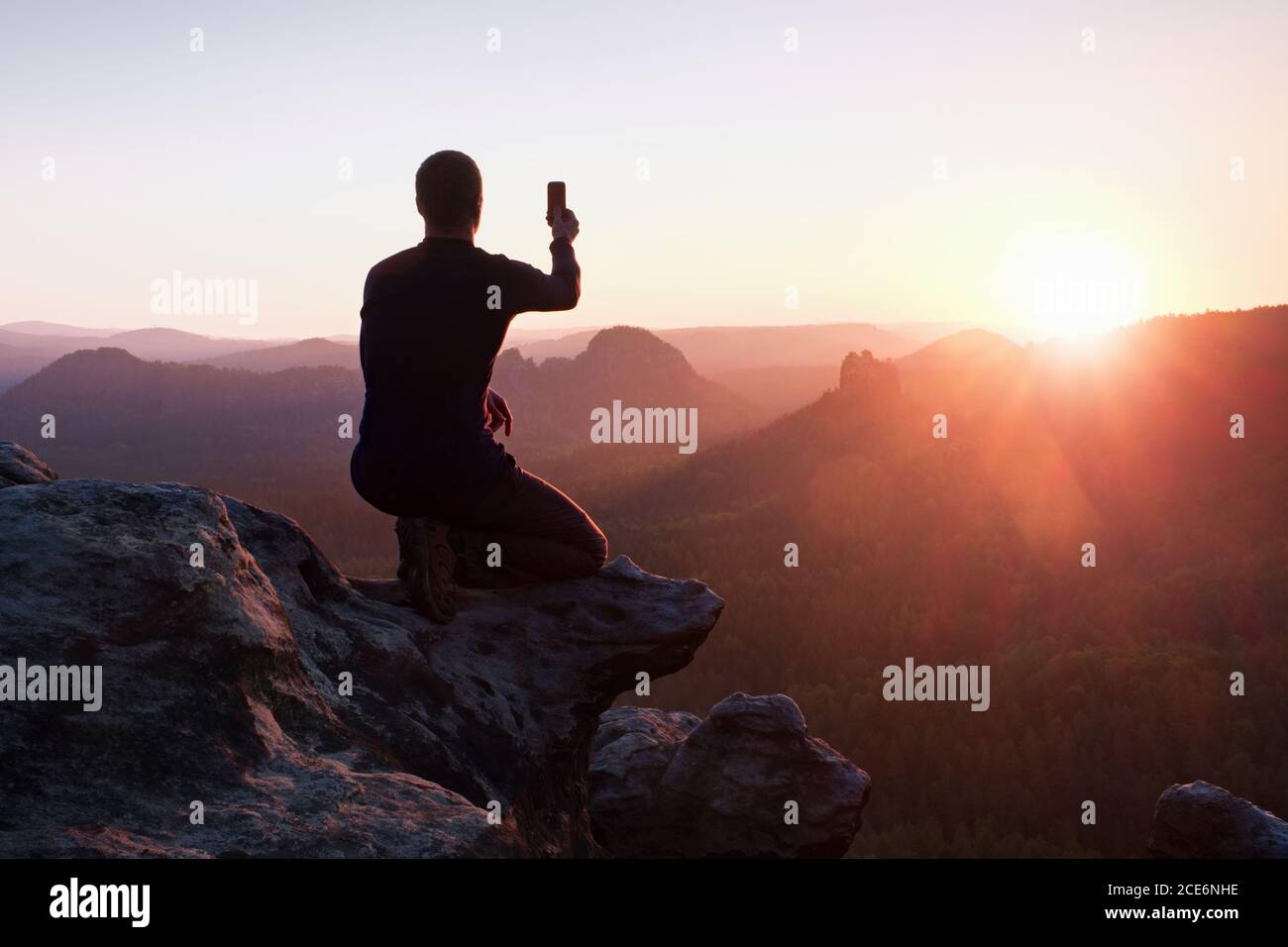 Short hair man in sportswear on cliff's edge and taking photos by smart  phone Stock Photo - Alamy