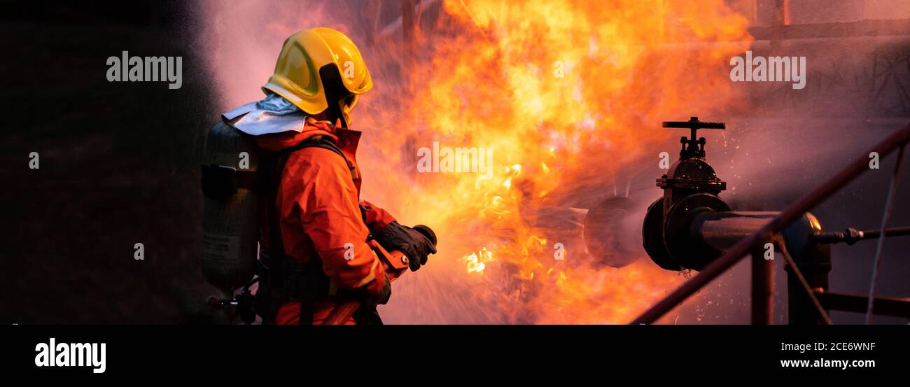 Panorama Firefighters use water fog spray down fire from oil rig factory explosion Stock Photo
