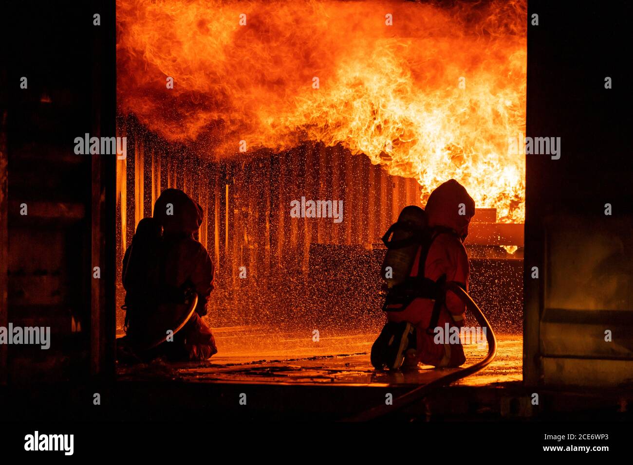 Firefighters use water fog spraying down fire flame in building. Stock Photo