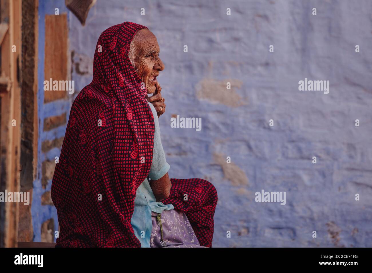 India - October 30, 2012: Side view of senior Indian female in traditional wear standing near shabby stone building and looking away Stock Photo
