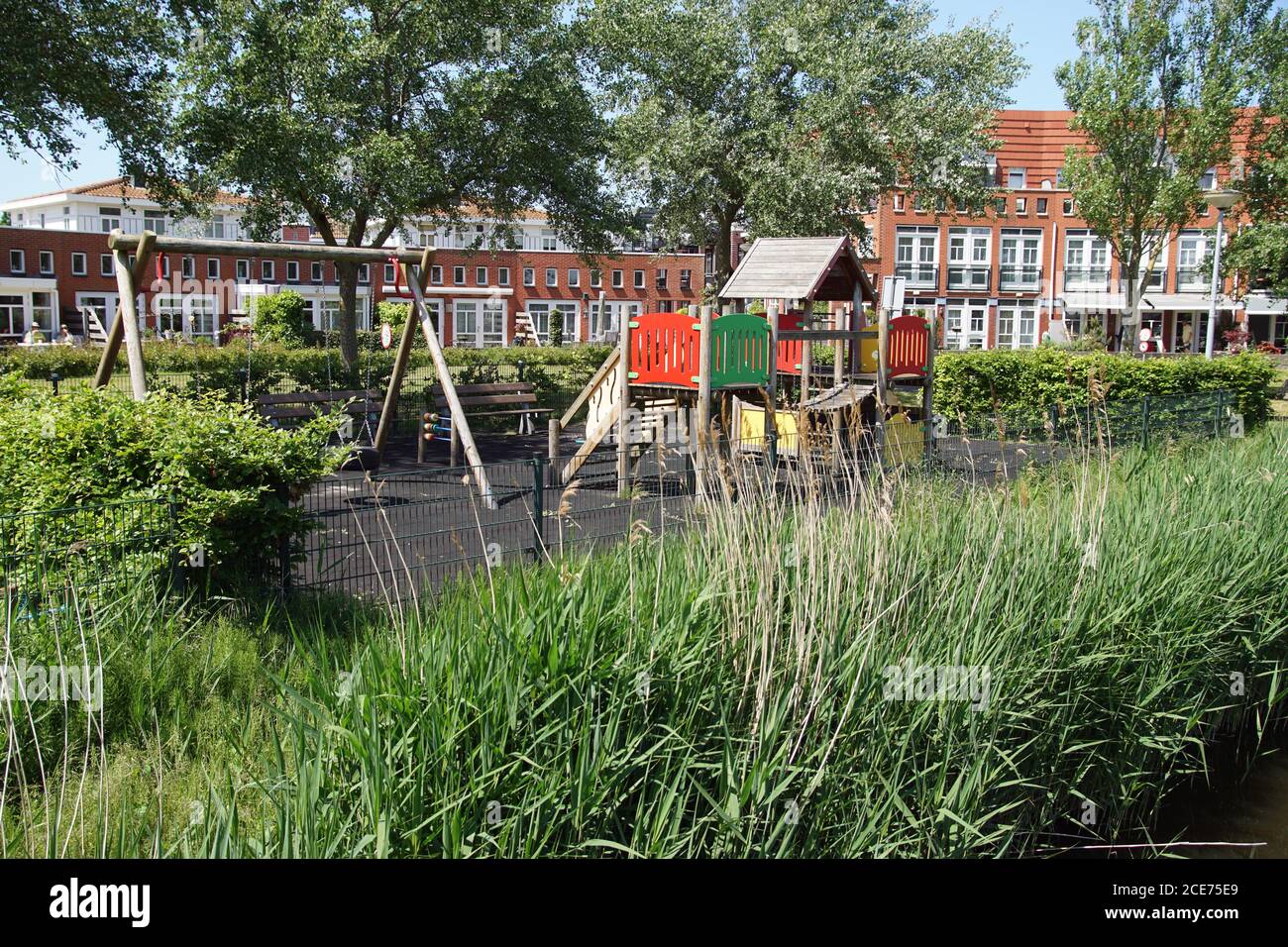Small playground with a climbing house, swing and bench in a new