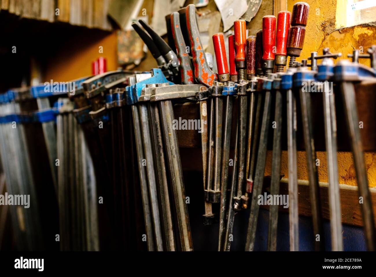Various metal tools and clamps for woodwork placed on shelf in shabby carpentry Stock Photo