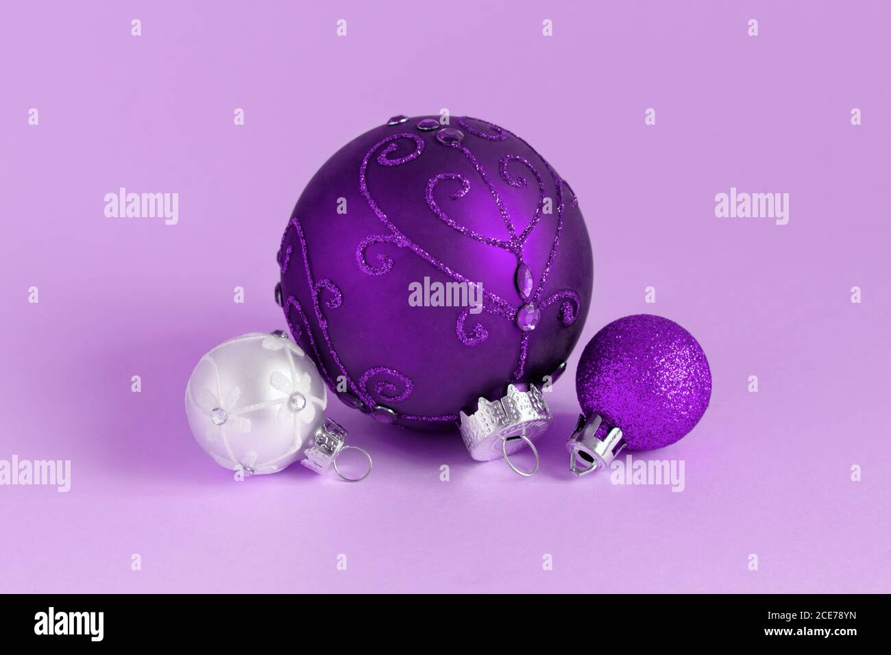 Purple and silver Christmas baubles on a lavender background close up