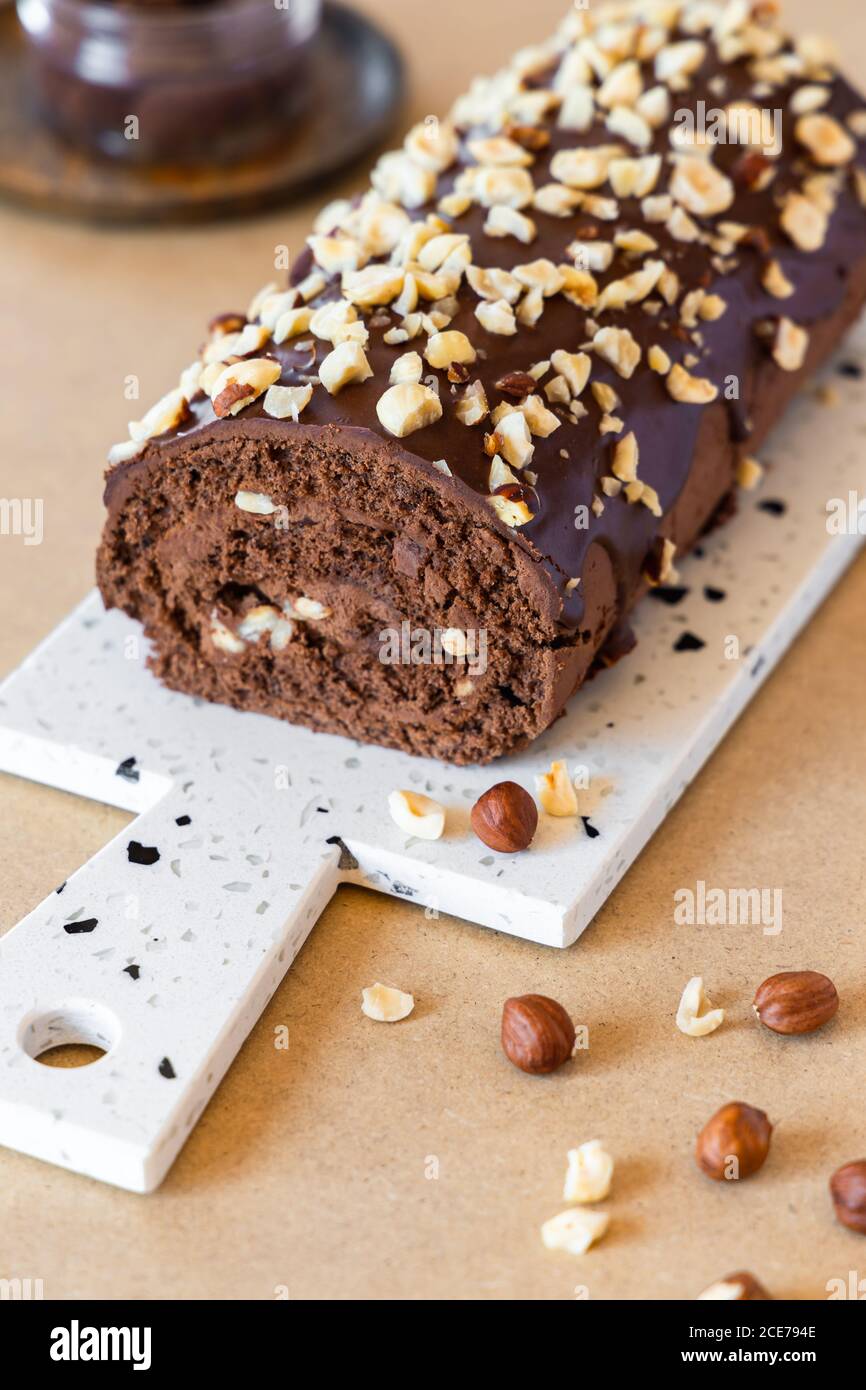 Delicious homemade roll cake with chocolate glaze and hazelnut placed