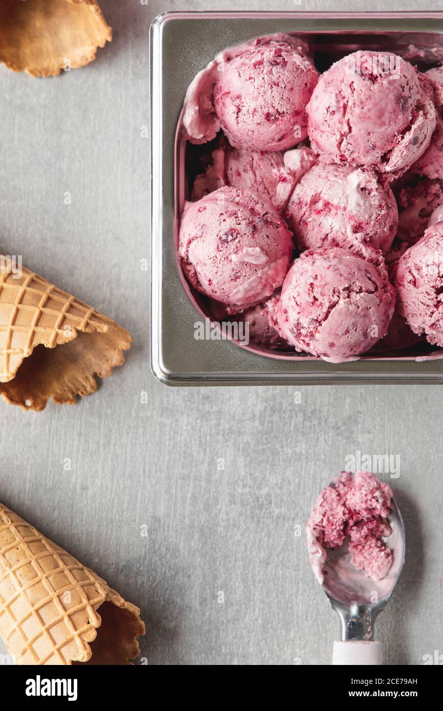 From above of delicious homemade cherry ice cream scoops arranged on table with waffle cones Stock Photo