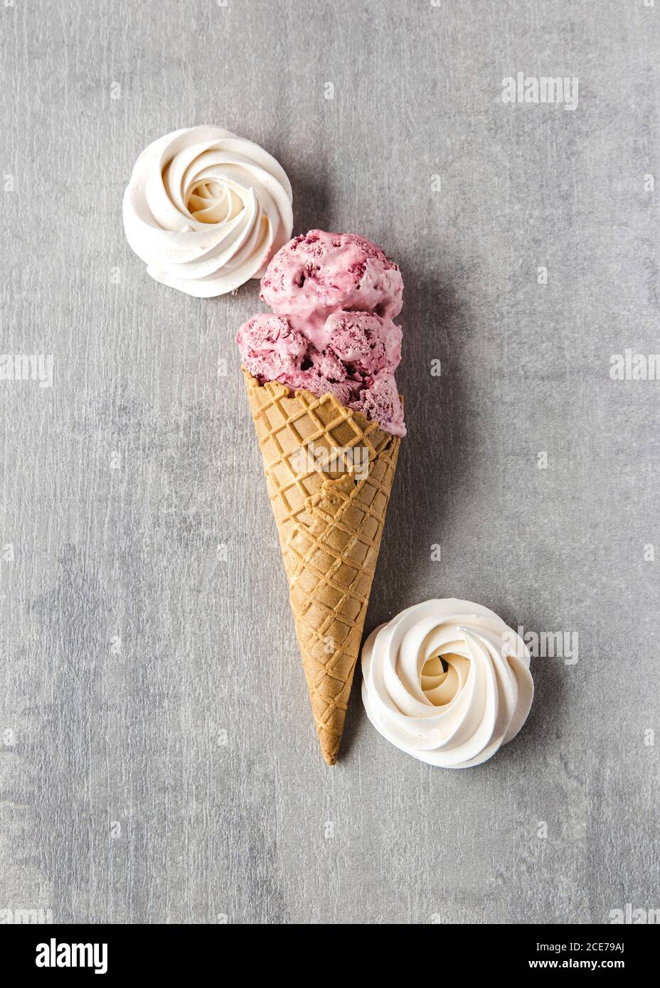 Top view of yummy homemade cherry ice cream in waffle cone placed on table with meringues Stock Photo